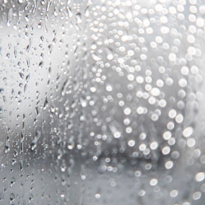 窓につく雨の水滴の写真