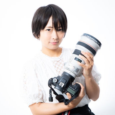 300mmの白レンズを抱える女性の写真