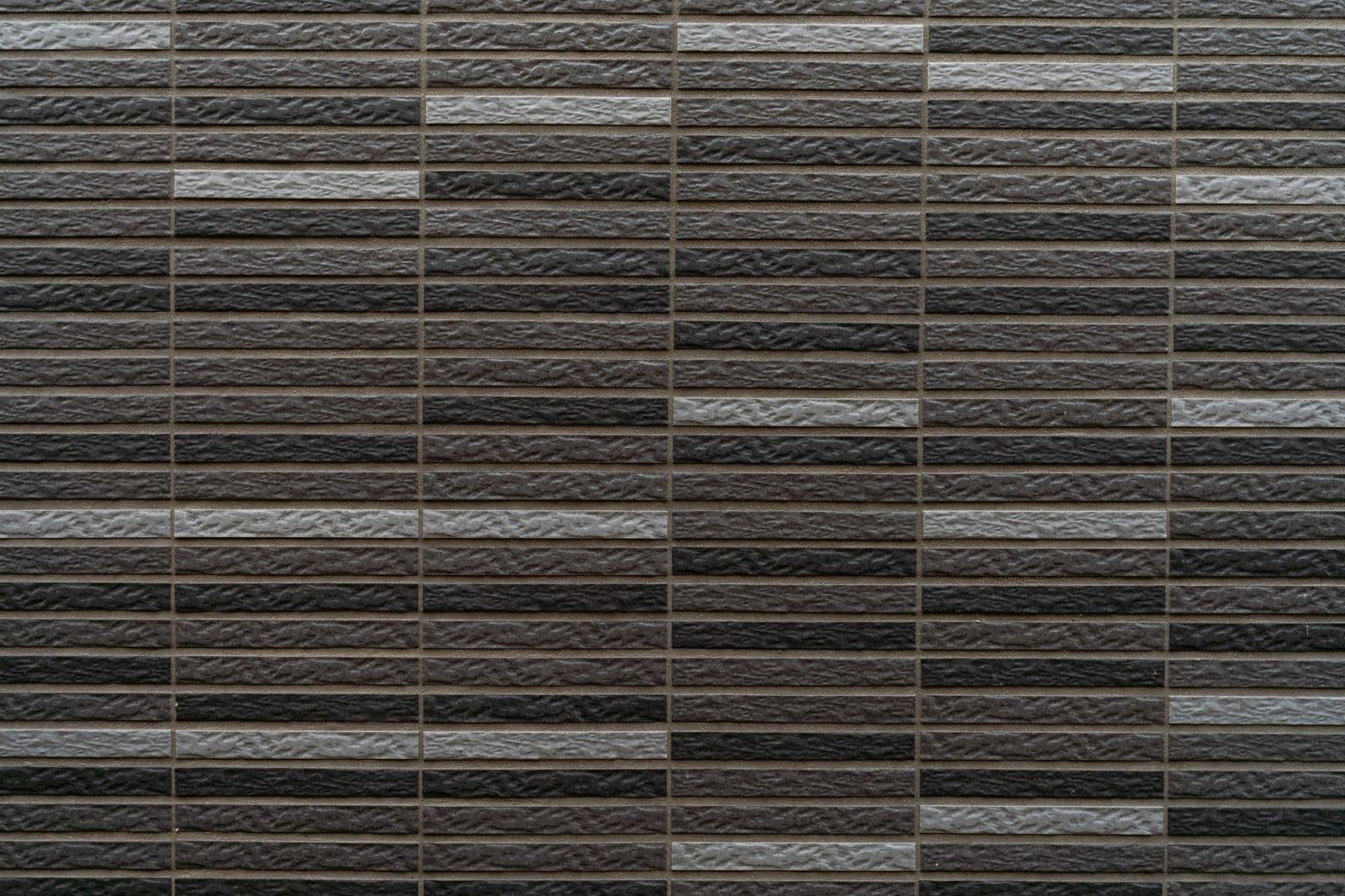 ブラウンとグレーの横長レンガタイルが規則正しく並んだテクスチャー