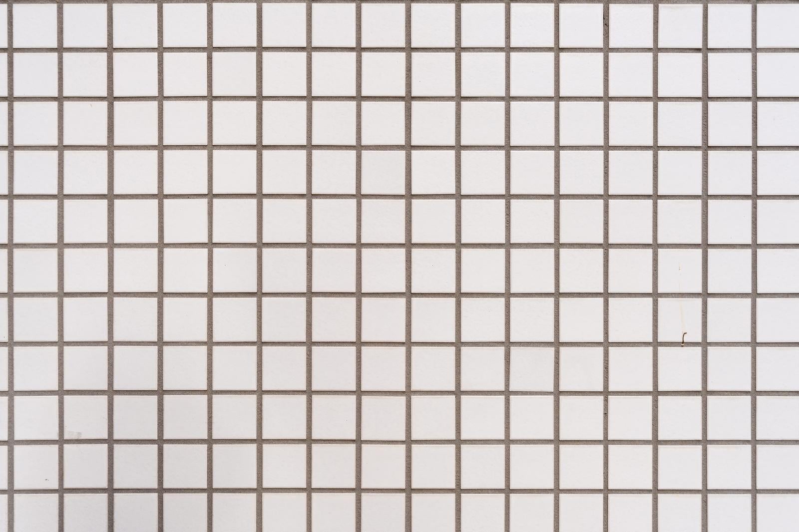 白い正方形タイルが規則正しく並んだ壁面のテクスチャ