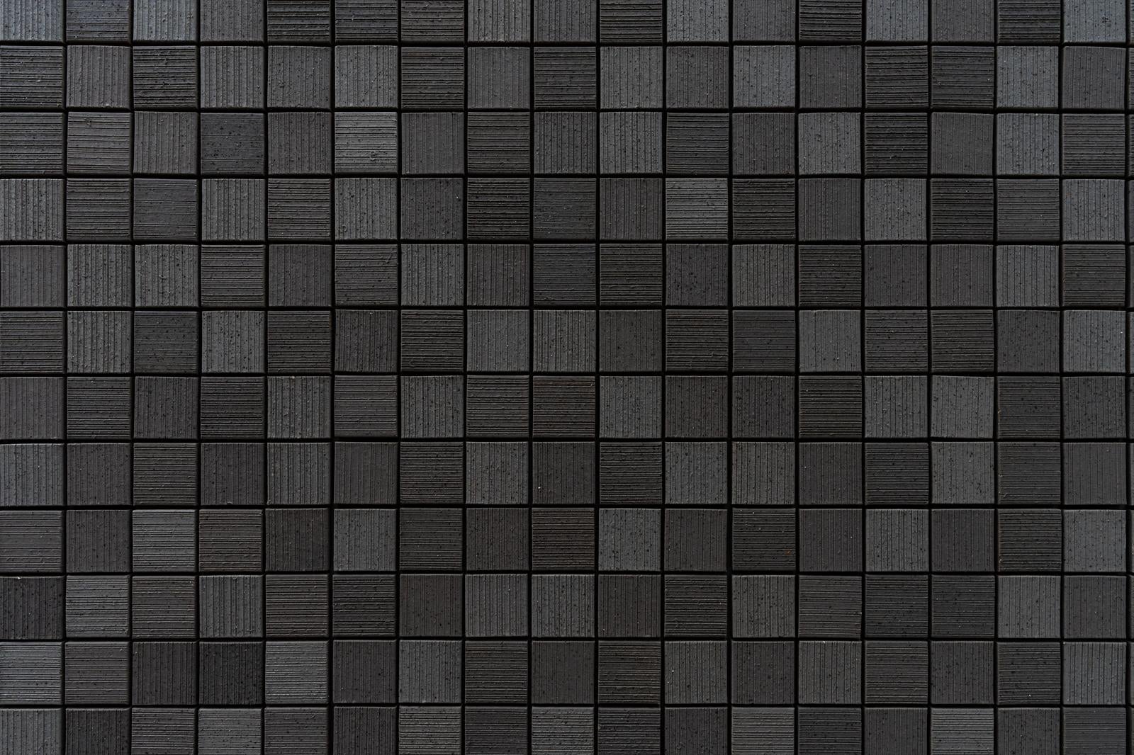 グレートーンの正方形モザイクタイルが規則正しく配置された壁面テクスチャ
