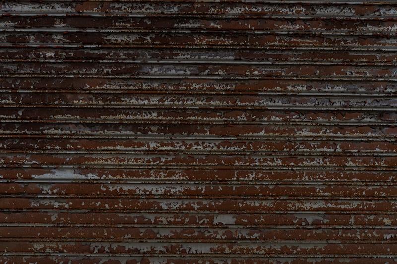 茶色いペンキが剥がれて劣化した横張りの木製板壁の写真