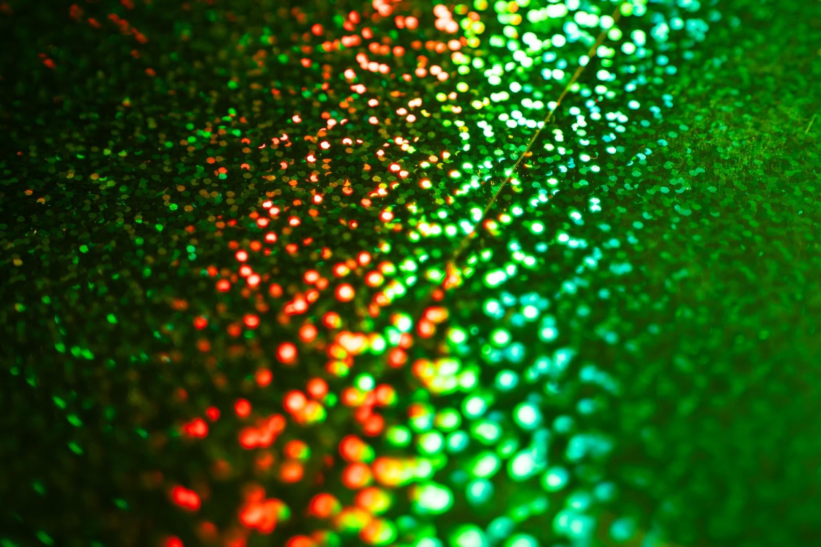 赤オレンジから緑へのグラデーションで光る粒子が美しくボケた抽象的な背景