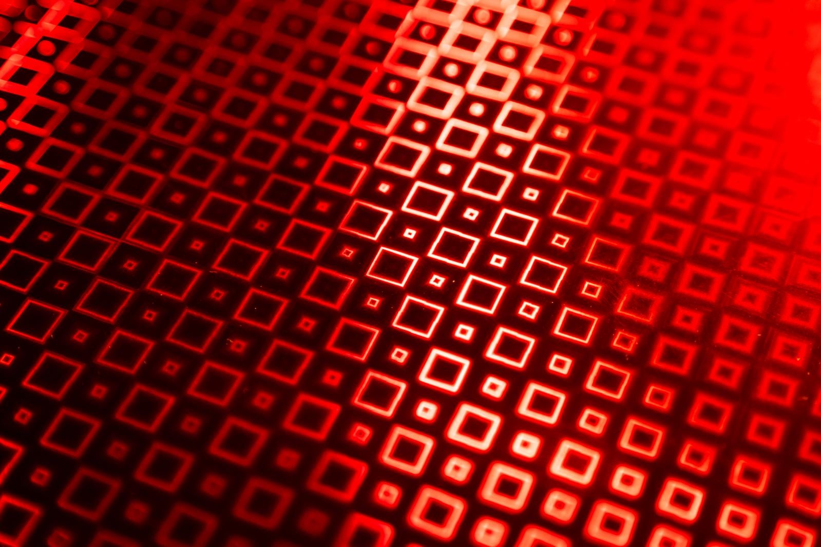 赤い光で照らされた正方形が規則的に配列された幾何学パターン