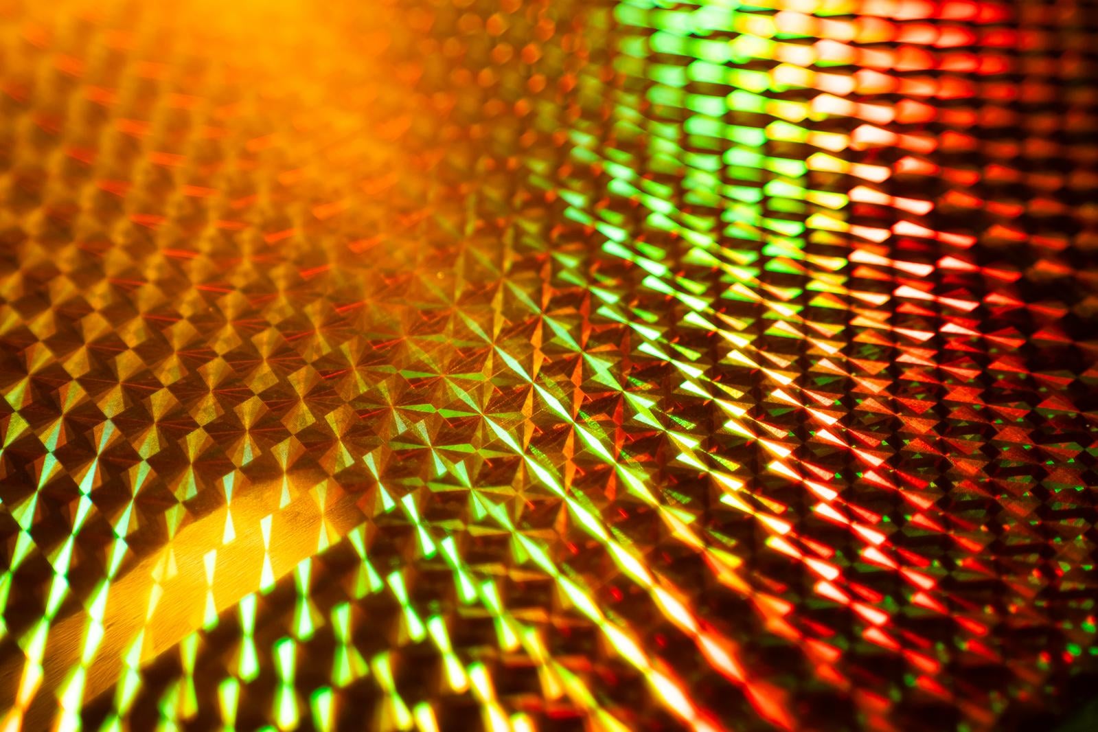 ホログラムシートのダイヤモンドカット模様に光が反射してオレンジや緑に変化するマクロ写真