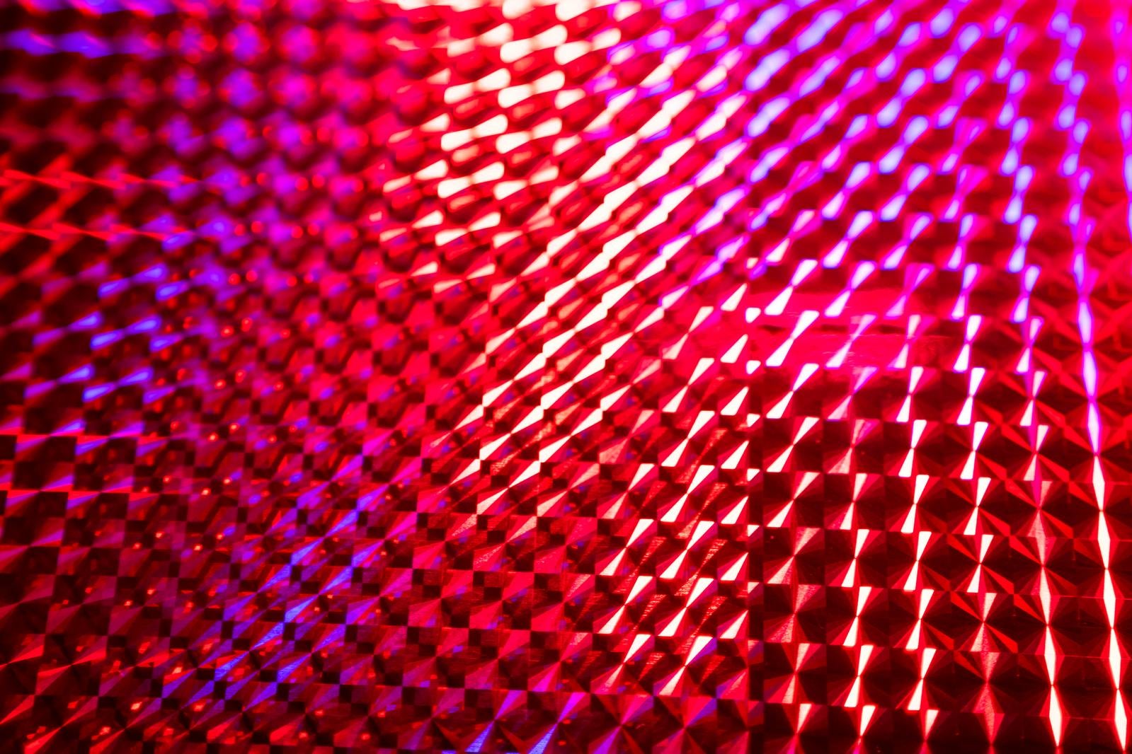 赤と紫の光を反射するホログラムシートの格子パターンを接写した写真