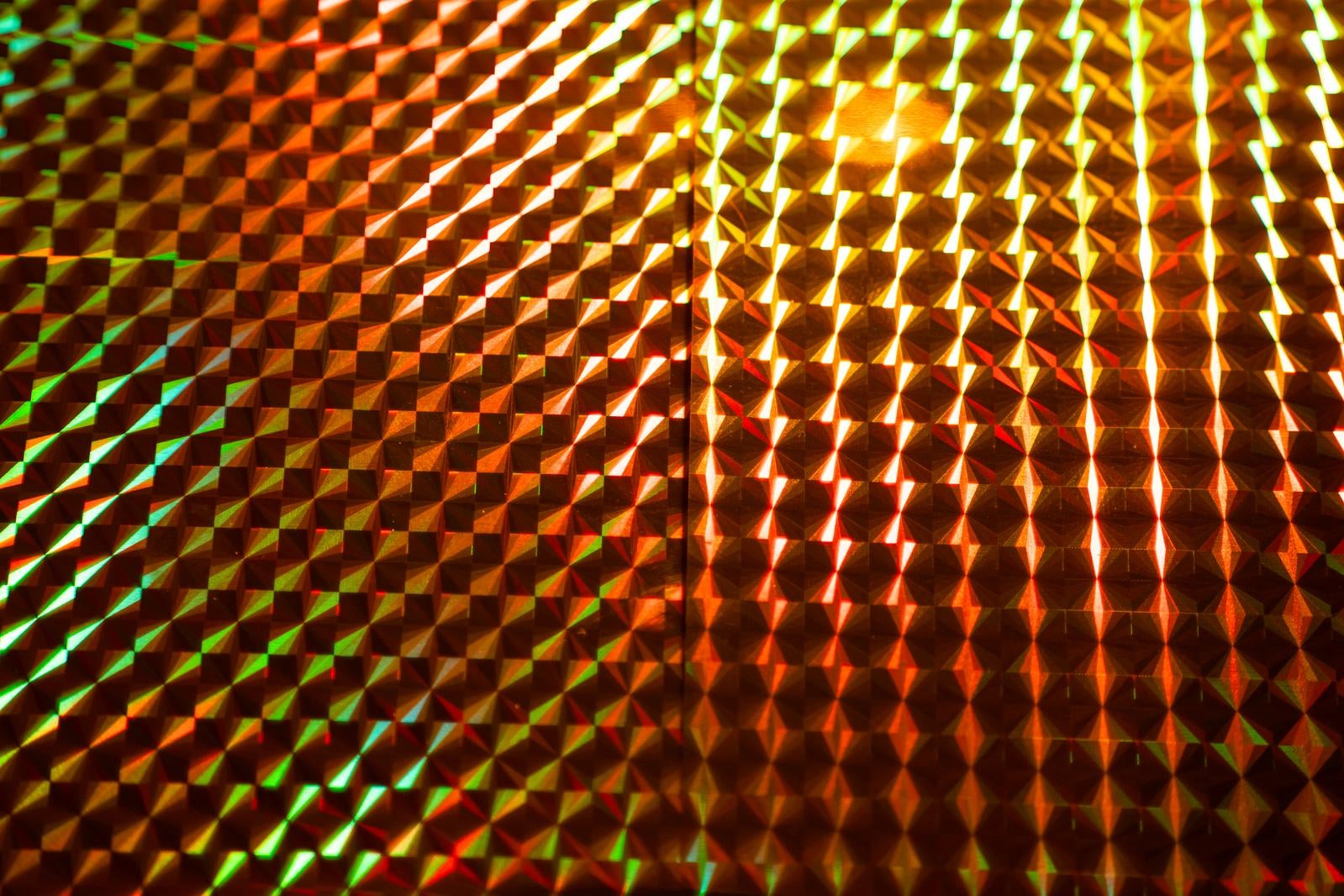緑と橙色のホログラム格子パターンがプリズム効果で立体的に輝く
