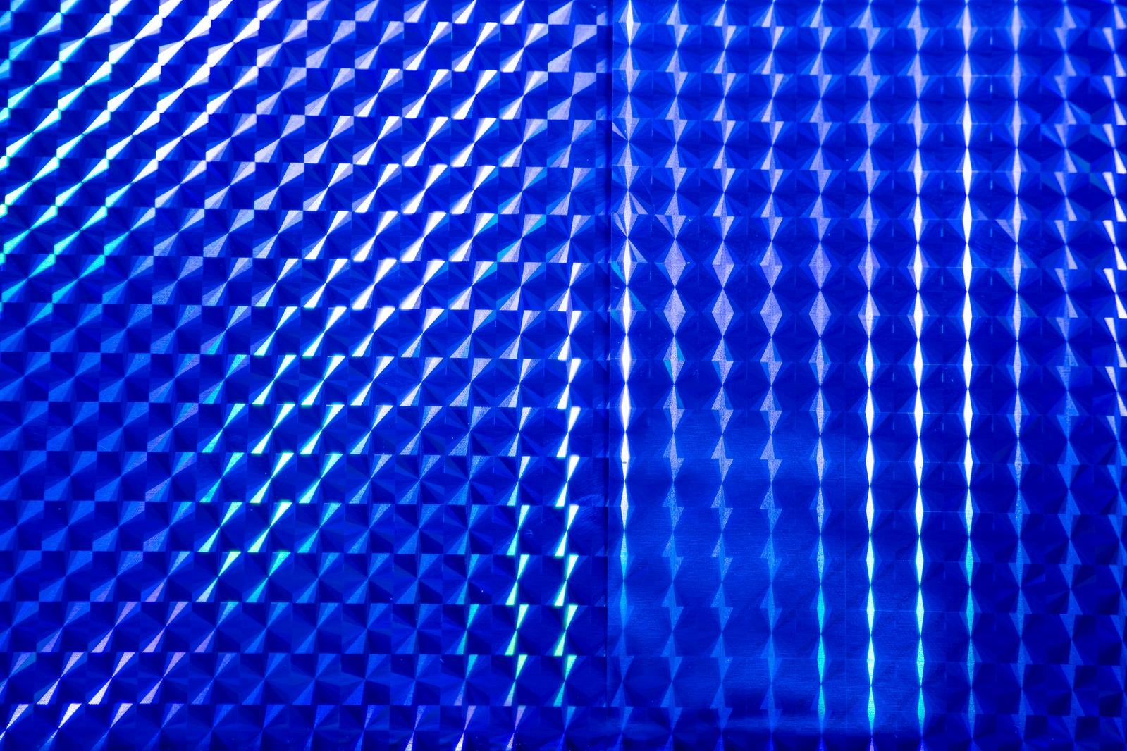 青い立体的なテクスチャーに光が反射し、幾何学的なパターンが輝く背景