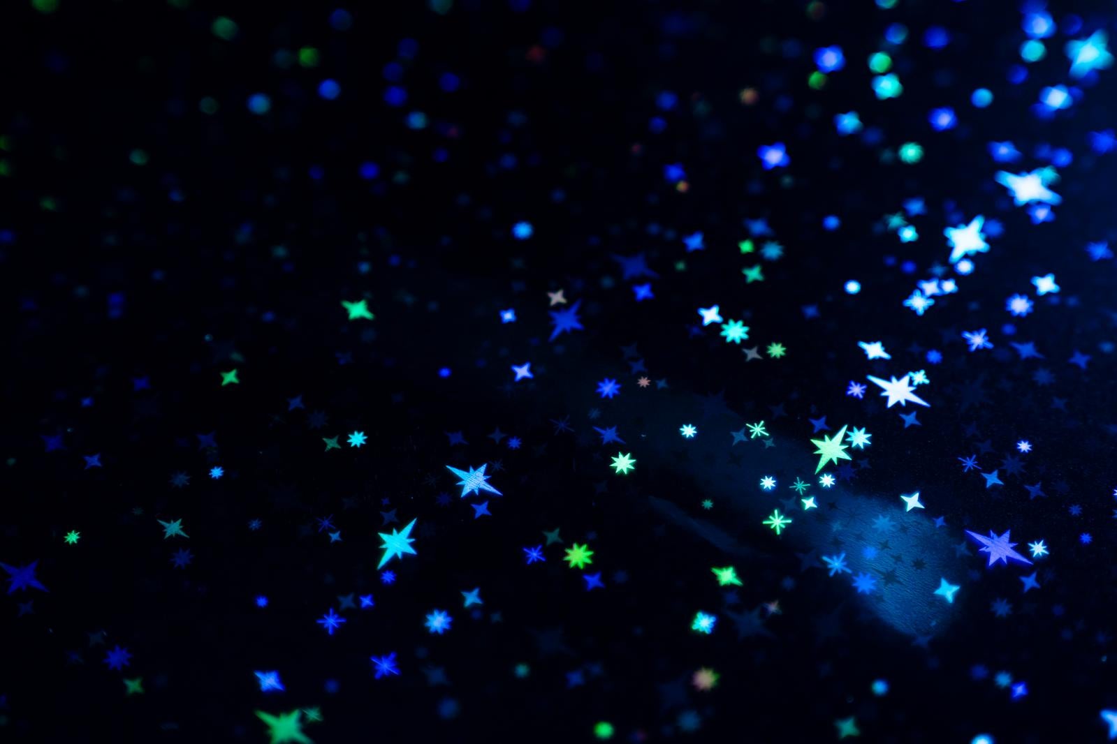 黒背景に青と緑の星とキラキラしたパーティクルが光り輝く
