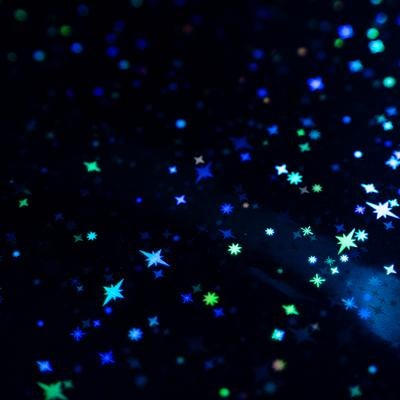 黒い背景に青と緑にきらめく星とキラキラパーティクルの写真