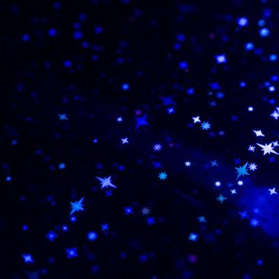 黒背景に散りばめられた青く輝く星とキラキラした光粒の写真