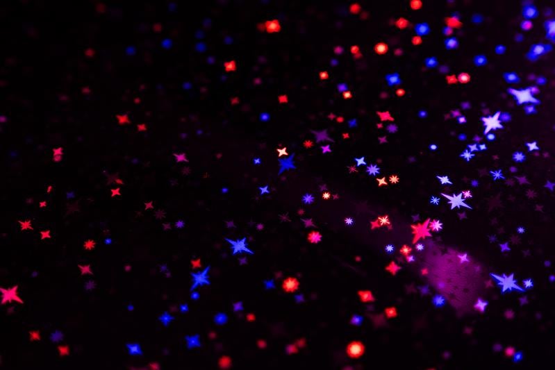 黒背景に赤と青に光るキラキラした星の粒子表現と輝きの背景