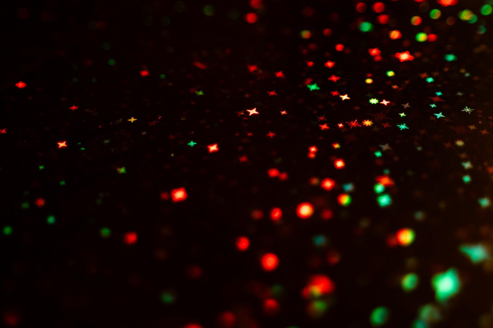 赤と緑のキラキラした光が浮かぶ黒い夜間背景