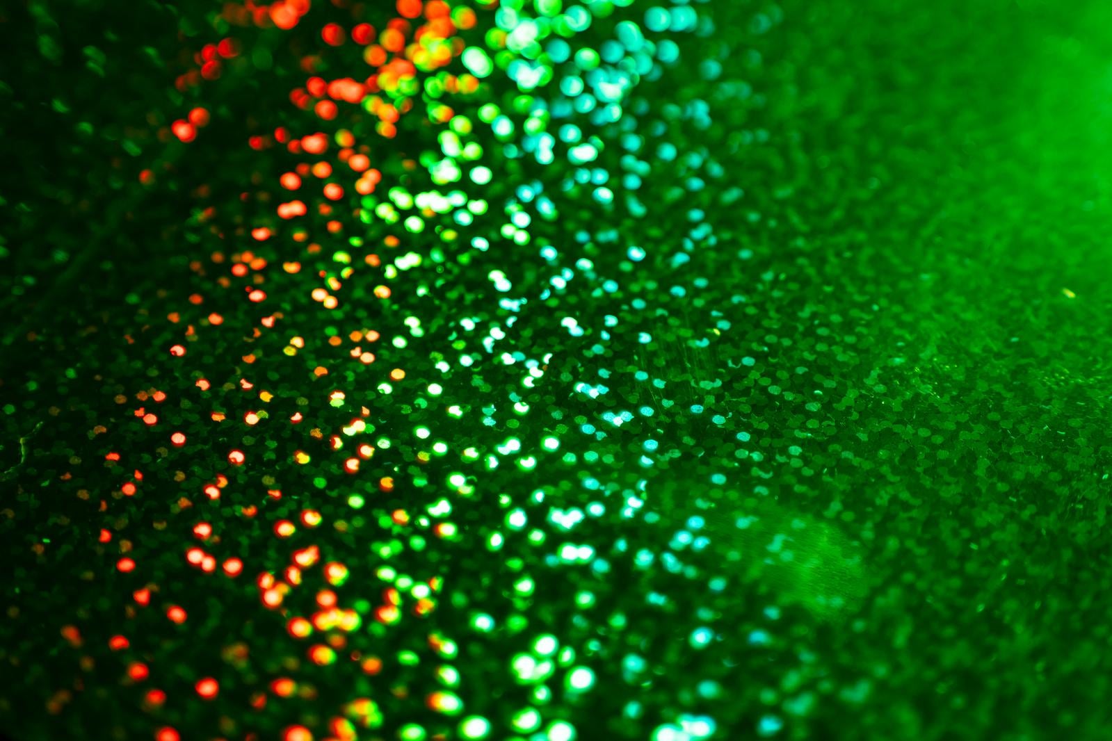 赤からグリーンへグラデーションする輝くキラキラ粒子の背景