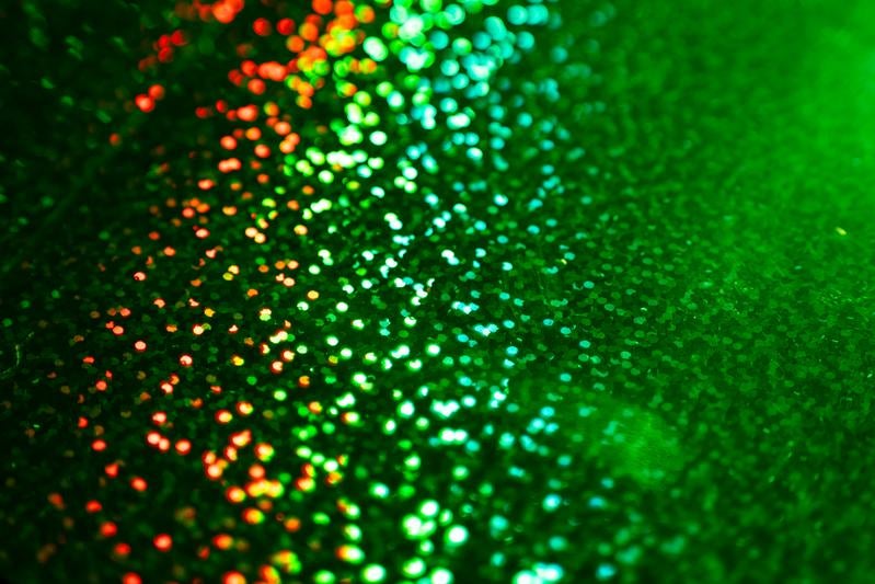 赤からグリーンへグラデーション状に輝く無数のキラキラ粒子