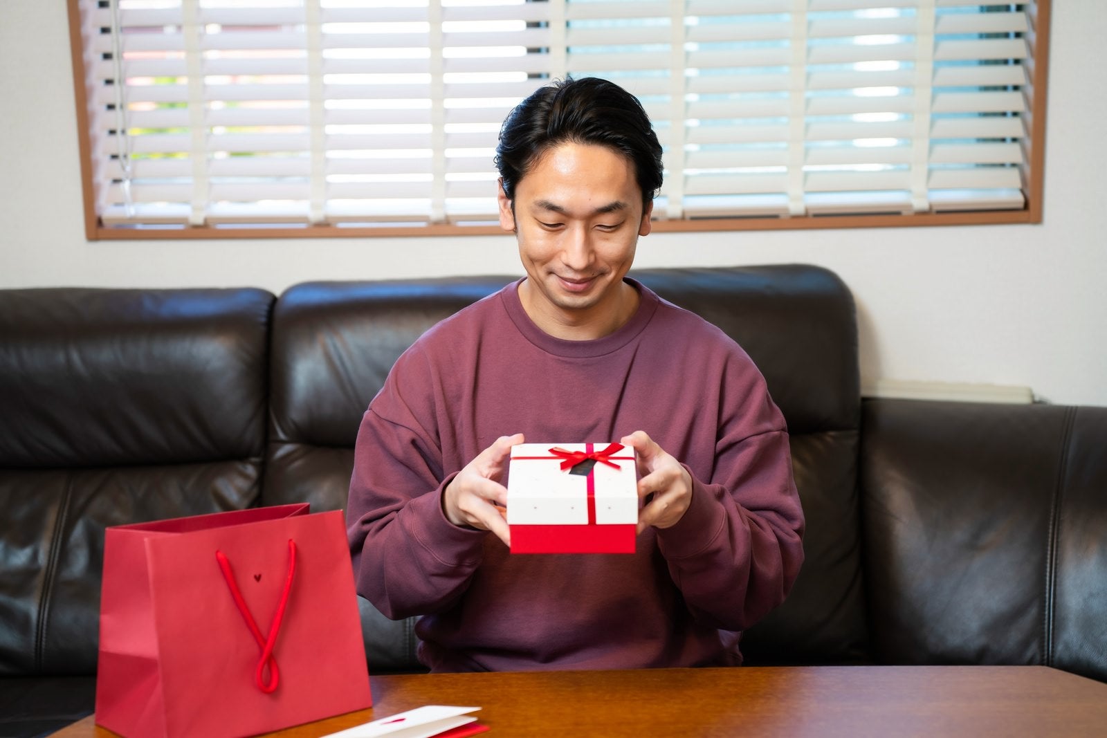 「バレンタインに女性社員からもらったプレゼントを開封する男性」の写真［モデル：大川竜弥］
