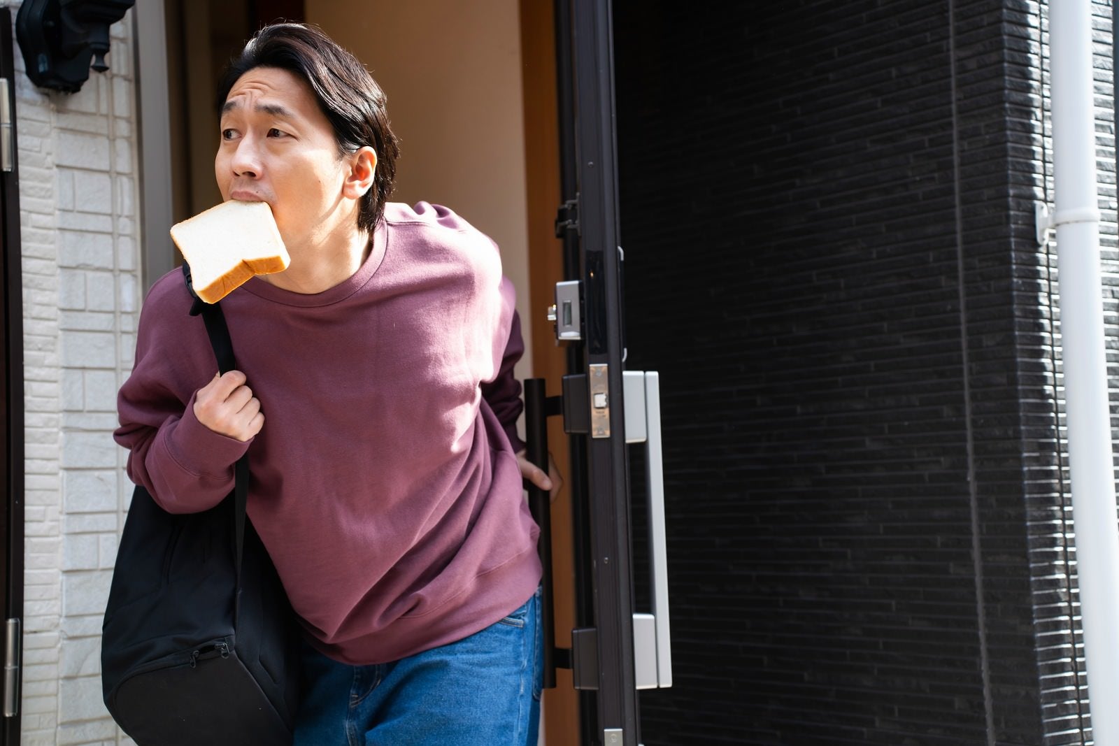 「出会いを求めて食パンを咥えながら家を出る男性」の写真［モデル：大川竜弥］