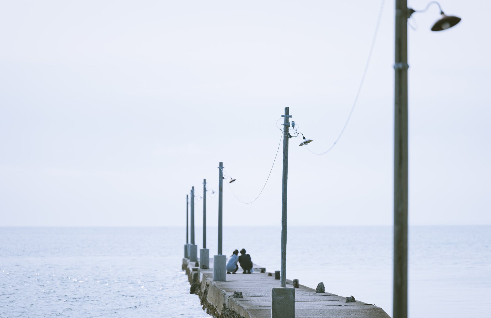 「原岡海岸の桟橋で記念撮影をする男女カップル」の写真