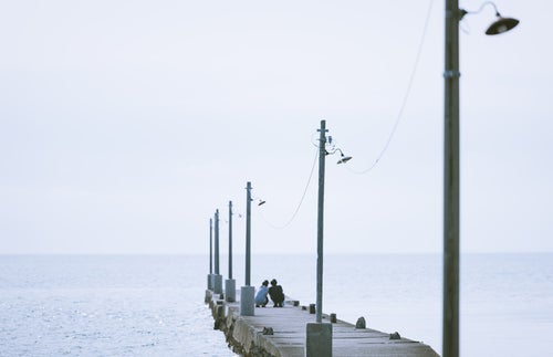 原岡海岸の桟橋で記念撮影をする男女カップルの写真
