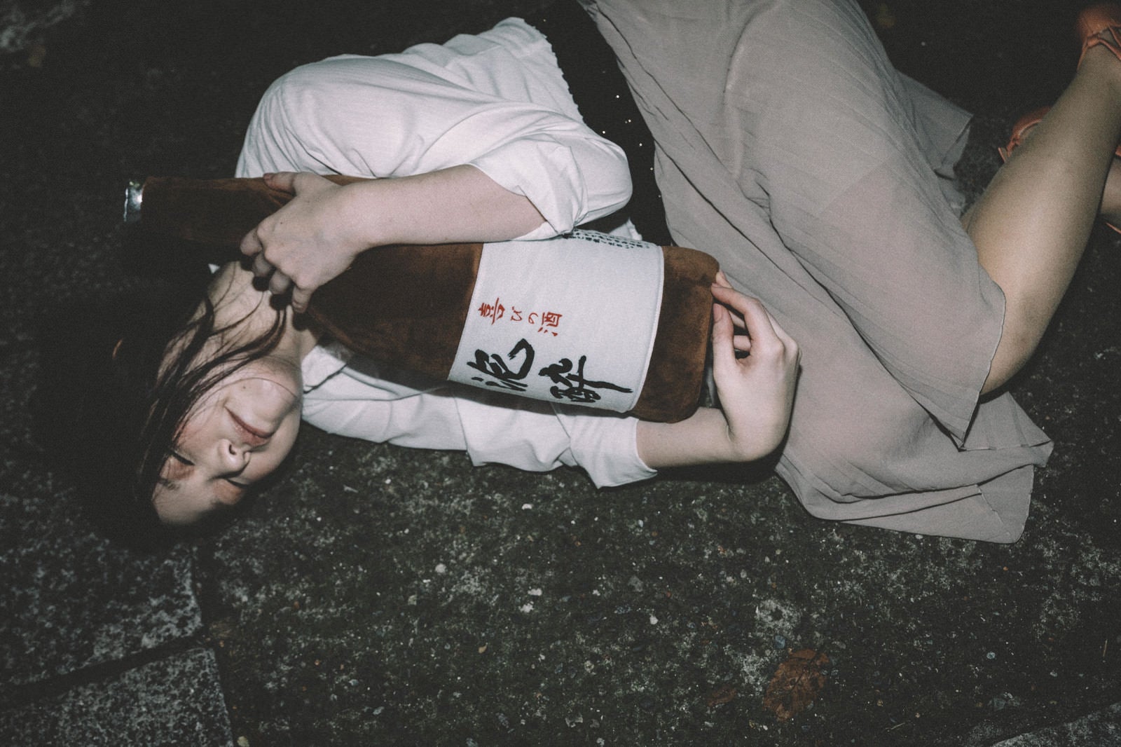「［忘年会シーズン］泥酔して一升瓶を抱きながら路上で寝てしまった女性」の写真［モデル：シマヅ］