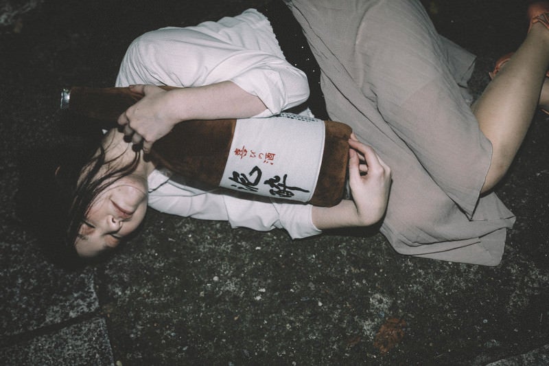 ［忘年会シーズン］泥酔して一升瓶を抱きながら路上で寝てしまった女性の写真