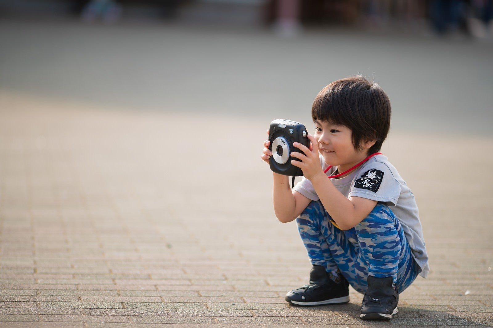 「インスタントカメラに興味津々の子供」の写真
