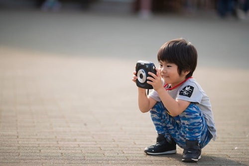 インスタントカメラに興味津々の子供の写真