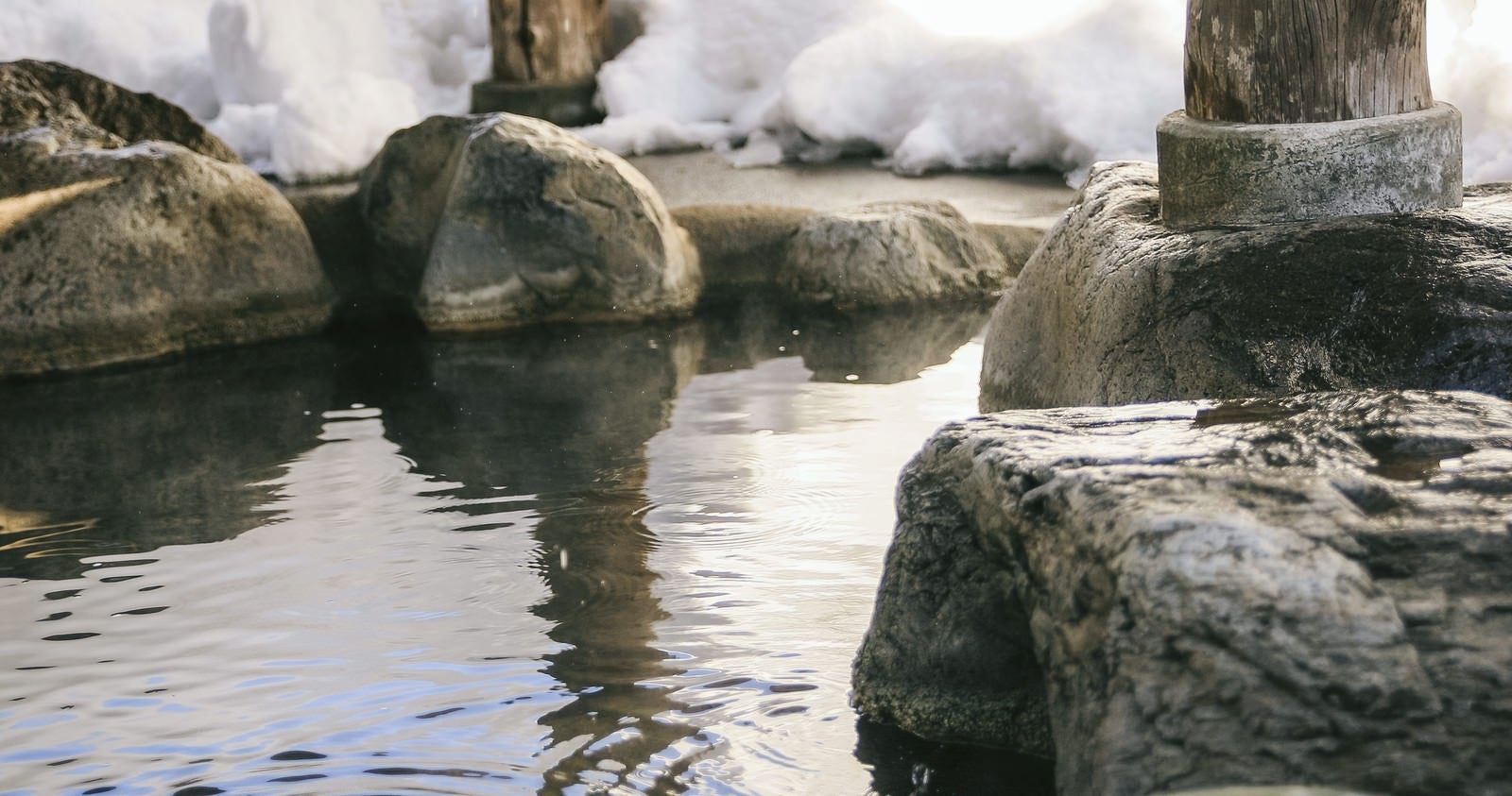 「腰を掛けると滑らかで心地よい岡田旅館の岩露天風呂」の写真