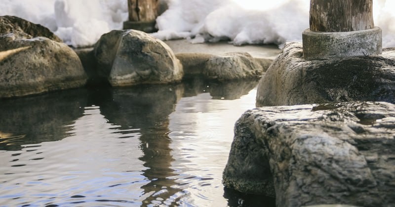 腰を掛けると滑らかで心地よい岡田旅館の岩露天風呂の写真