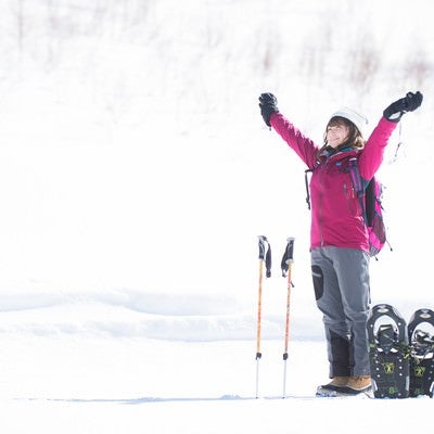 雪山のトレッキングで大きく伸びをする女性の写真