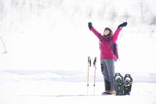 雪山のトレッキングで大きく伸びをする女性の写真