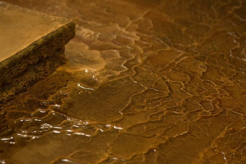 源泉かけ流しの証である波状に溶けた「栄太郎」の浴場の床の写真