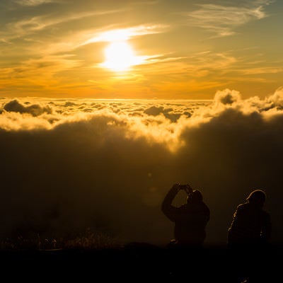夕暮れの雲海の絶景に感動するカップルの写真