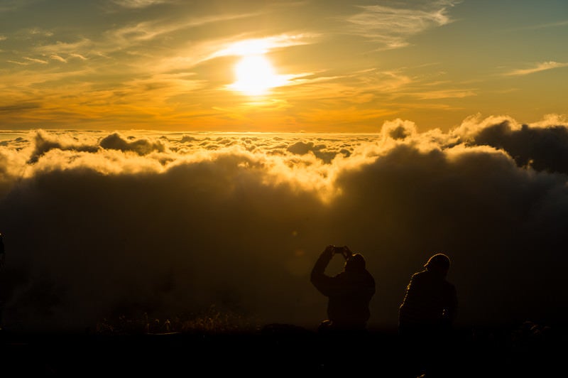 夕暮れの雲海の絶景に感動するカップルの写真