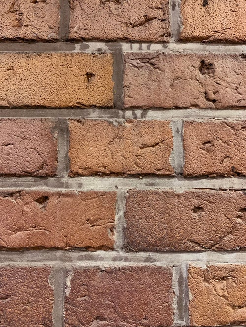 隙間をコンクリートで固められた煉瓦（テクスチャー）の写真