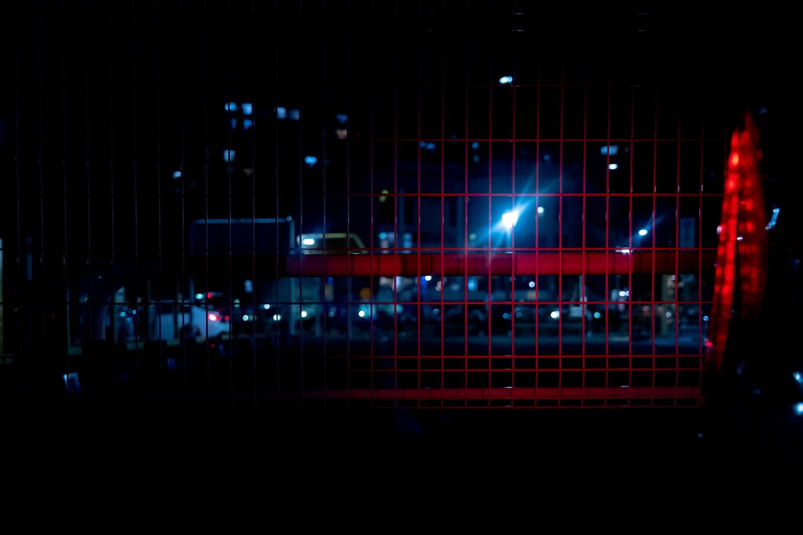 「赤色ライトが反射するメッシュフェンス」の写真