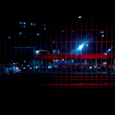 赤色ライトが反射するメッシュフェンスの写真