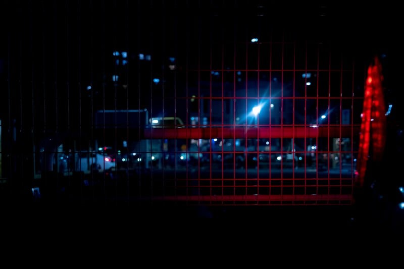 赤色ライトが反射するメッシュフェンスの写真