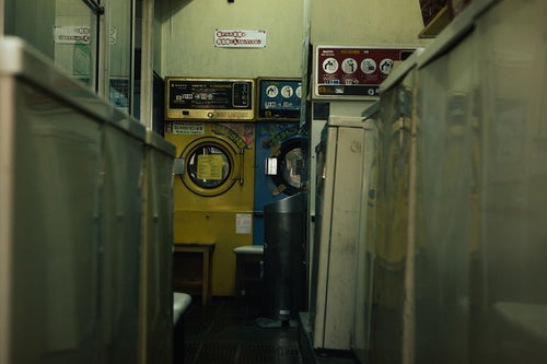 昭和レトロな洗濯機が並ぶコインランドリーの写真