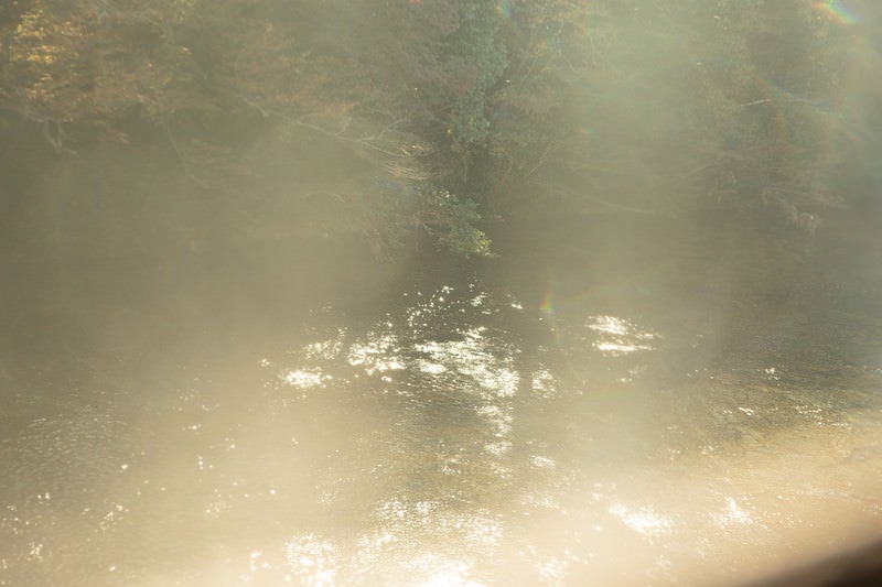 靄がかる湖面に反射する日の光の写真