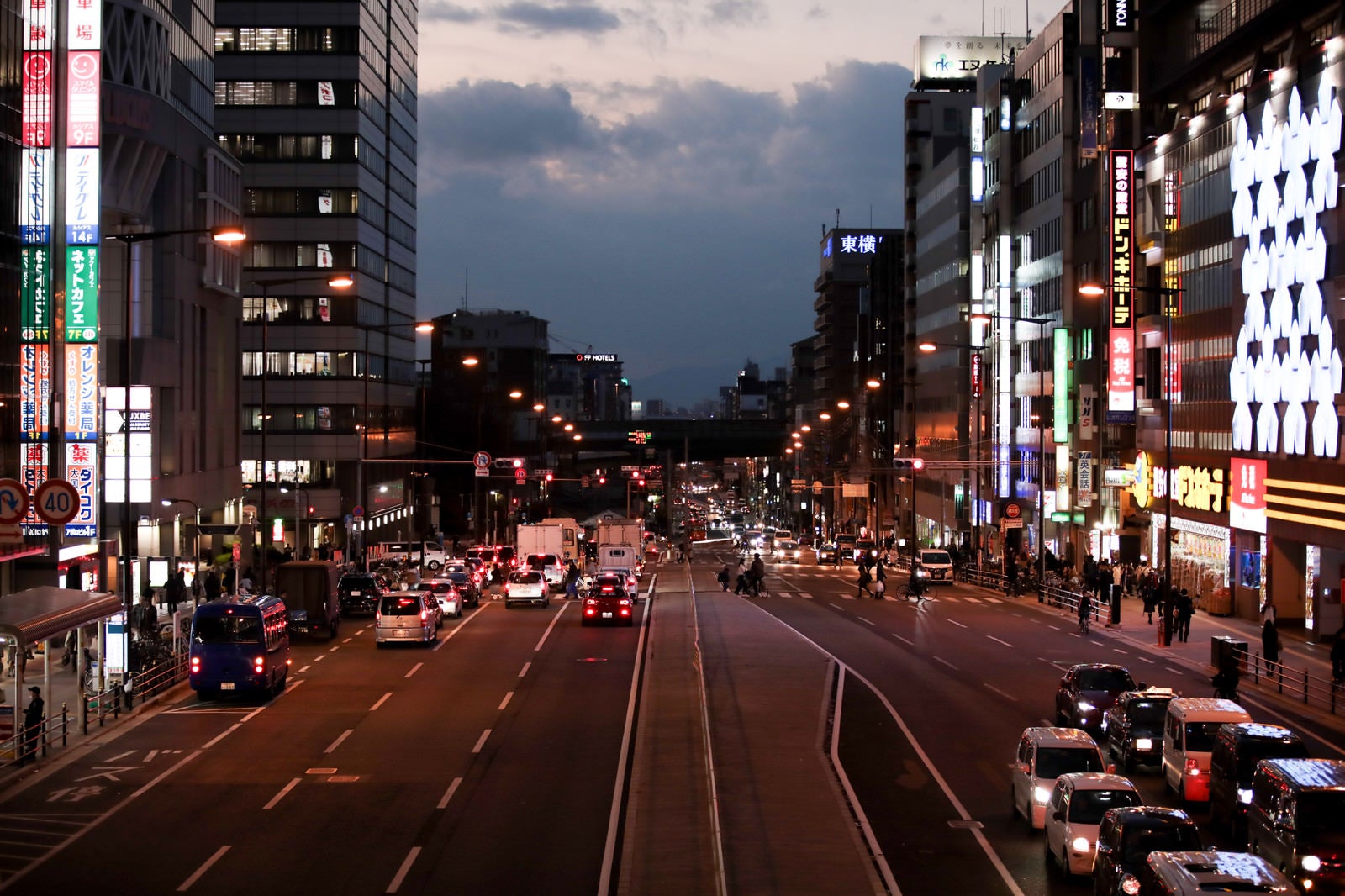 「赤信号で止まる車と街並み」の写真