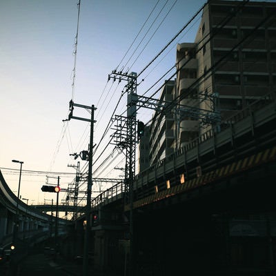 青空に張り巡る電線と高架橋の写真
