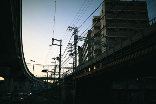青空に張り巡る電線と高架橋の写真