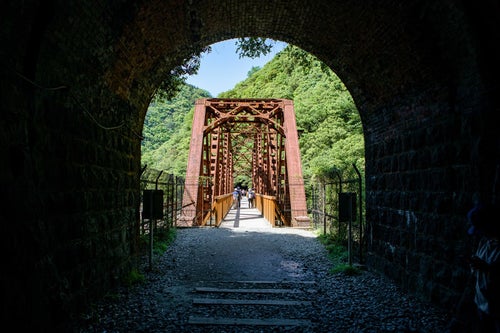 トンネルから見た赤い鉄道橋（JR福知山線廃線敷）の写真