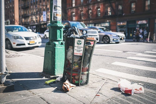 ニューヨークの街角のゴミ箱と散乱するゴミの写真