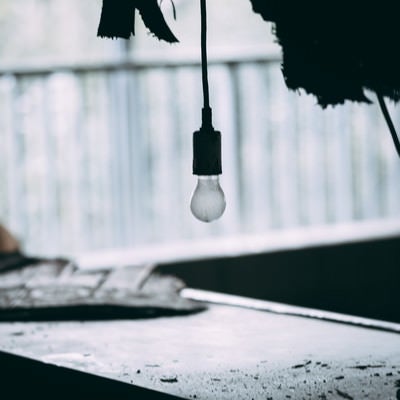 廃墟でぽつんと垂れ下がる豆電球の写真