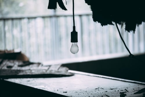 廃墟でぽつんと垂れ下がる豆電球の写真