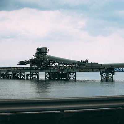 ガードレール越しに見る海上の工場の写真