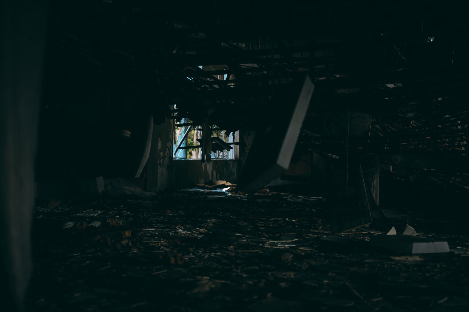 「暗がりから見る天井が崩れ落ちる廃墟」の写真
