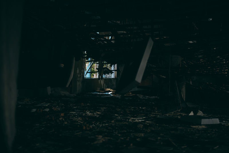 暗がりから見る天井が崩れ落ちる廃墟の写真